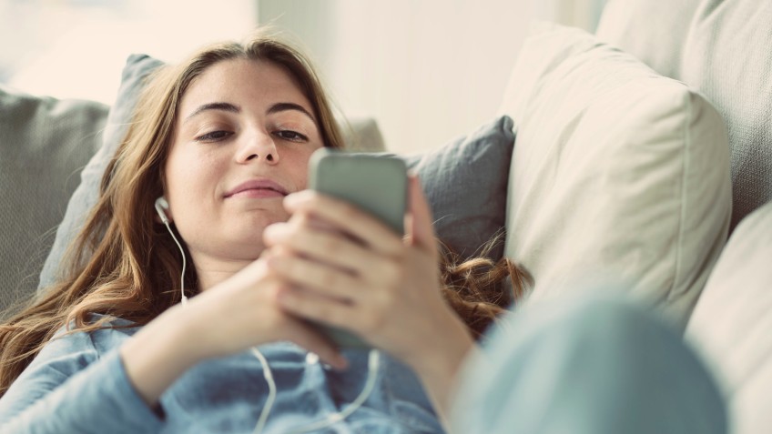 Joven se relaja viendo vídeos cortos en el sofá