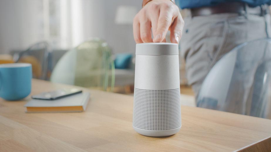 Mano de hombre enciende un altavoz inteligente, cuyo uso en Voice Shopping es tendencia del audio digital en 2022