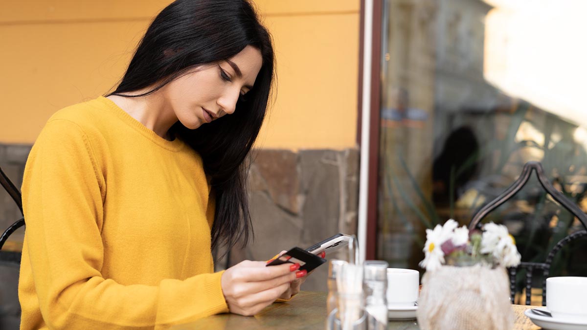 Una mujer realiza una compra online con su móvil en un e-commerce usando su tarjeta de crédito