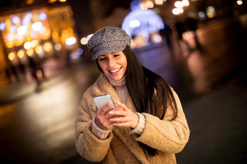 Uma mulher consulta seu smartphone na rua durante o inverno